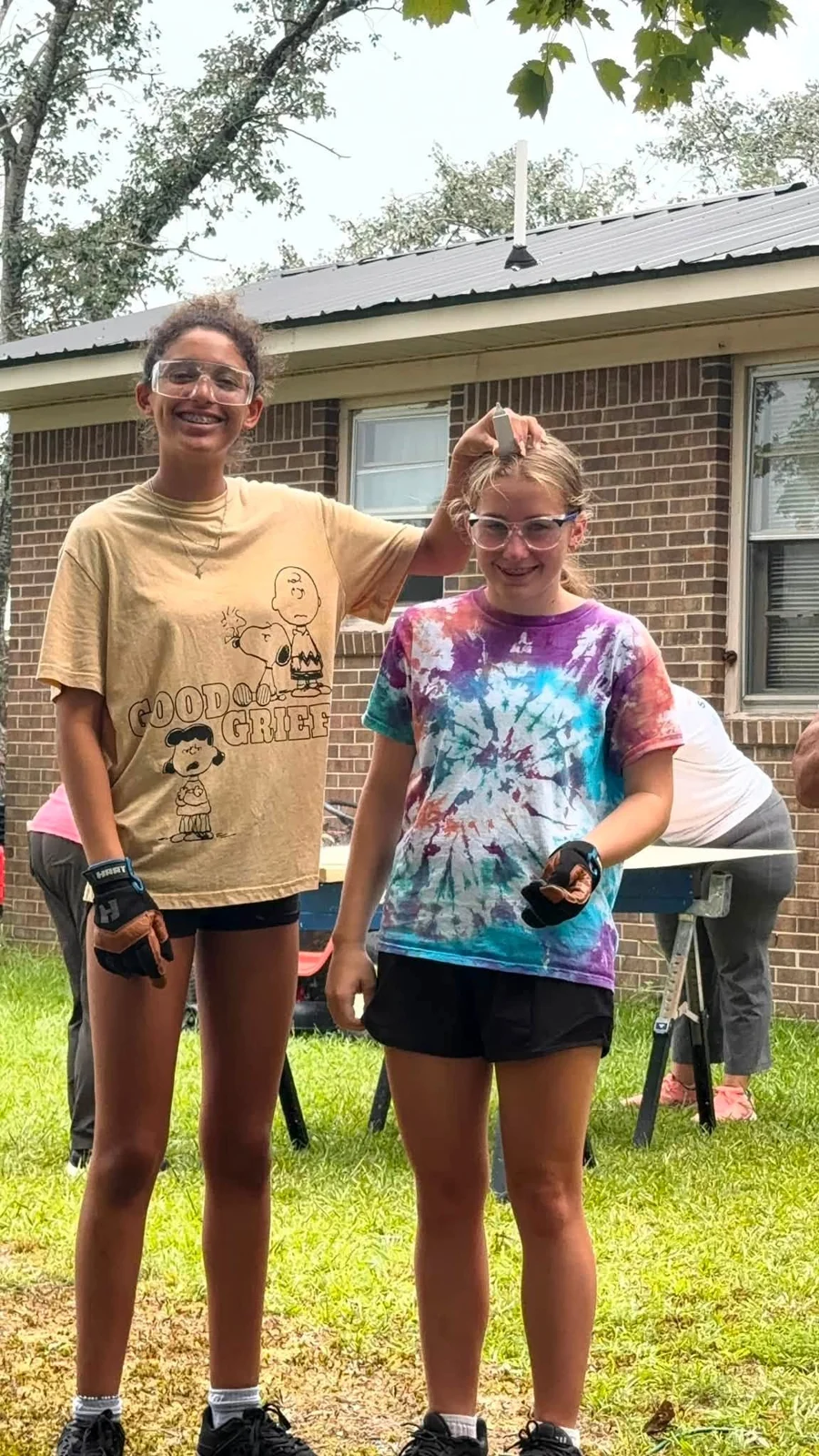Two young volunteers standing outside a home